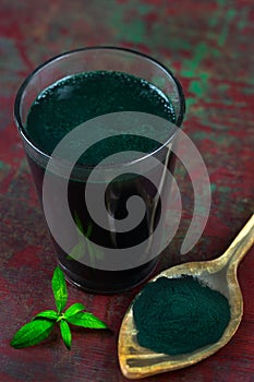 Organic green spirulina powder top view on wooden spoon background. Super foods,