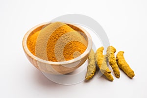 Organic Haldi or Turmeric powder spice pile in a bowl with whole, selective focus