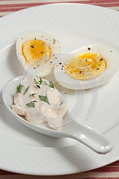 Organic hard boiled egg,halved with a spoon of mayonnaise with parsley