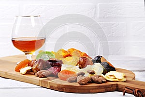 Organic Healthy Assorted Dried Fruit and glasses with cognac or whiskey on wine board. Selective focus.