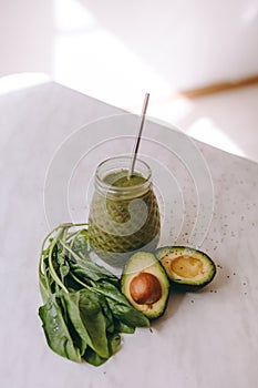 Organic and healthy green smoothie with banana, spinach, avocado, citrus fruits and chia seeds in a glass bottles on a rustic