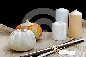 Organic and healthy pumpkins, three candles, and some wooden sticks on rustic background