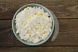 Organic homemade cottage cheese or curd in bowl on wooden rustic background with copy space Flat lay. Top view.