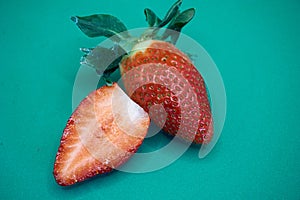 Organic juicy strawberry cut in half on a turquoise background