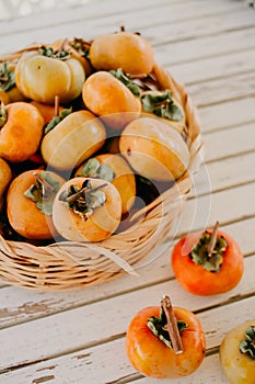 Organic Khakis fruit in a wicker basket. Persimmons