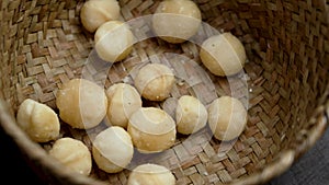 Organic macadamia nuts in a rustic wicker bowl. Delicious high-calorie snack