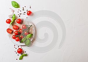 Organic Mini San Marzano Tomatoes on the Vine with basil and pepper on chopping board on white kitchen background. Space for text