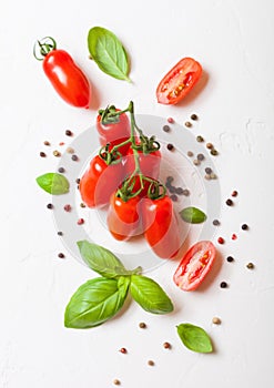 Organic Mini San Marzano Tomatoes on the Vine with basil and pepper on white kitchen background