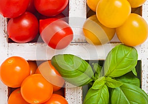 Organic Mini Tomatoes with basil and pepper in wooden box on stone kitchen background. San Marzano, orange and cherry tomatoes