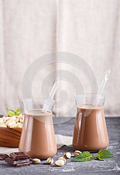 Organic non dairy pistache chocolate milk in glass and wooden plate with pistache nuts on a gray concrete background