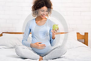 Organic nutrition. Excited pregnant woman eating apple