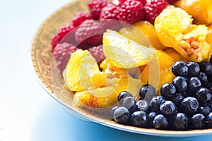 Organic oatmeal porridge in white ceramic bowl with raspberries, peaches and blueberries. Healthy breakfast - health and diet conc