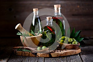 Organic olive oil with spices and herbs on an old wooden background. Healthy food.