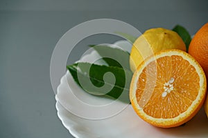 Organic orange and lemon on white plate with the gray background