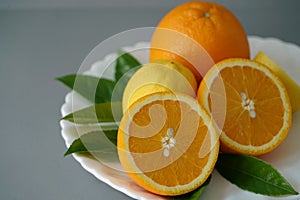 Organic orange and lemon on white plate with the gray background