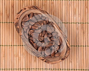 Organic pine nuts in shell in olive wood bowl