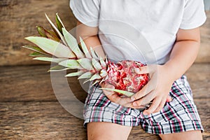Organic pink pineapple in hands on the old wooden background