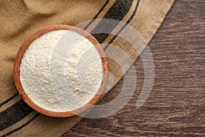 Organic quinoa flour in bowl on wooden table, top view. Space for text