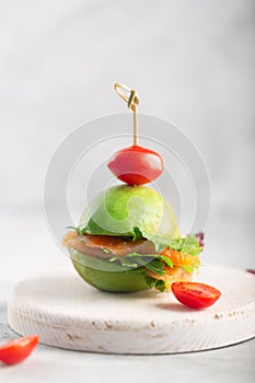 Organic raw avocado burger with salted salmon and fresh vegetables