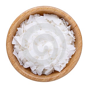 Organic raw coconut chips in wooden bowl isolated on white. Top view