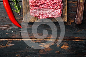 Organic Raw Grass Fed Ground Beef, on old dark  wooden table background, top view flat lay  with copy space for text