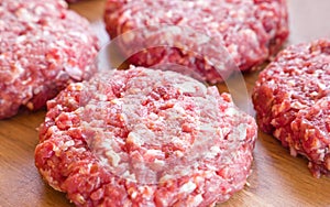 Organic raw ground beef, round patties for making homemade burger on wooden cutting board