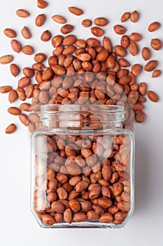 Organic red-brown peanuts Arachis hypogaea,  spilled and in a glass jar,
