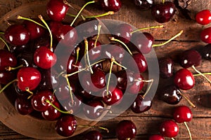 Organic red cherries in rustic plate on the wooden  background