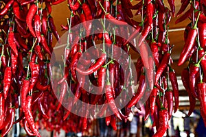 Organic red hot chili peppers hanging outdoors on market, closeup