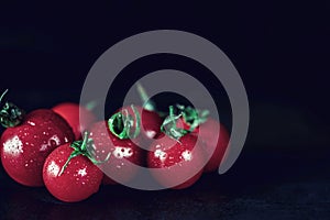 Organic red tomatoes on a black wooden slate, close up