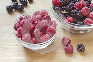 Organic ripe berries with raspberries and blackberries in a glass jar on a wooden table
