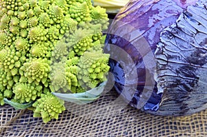 Organic ripe green Romanesco broccoli Roman cauliflower and Scotch kale or red cabbage on a sack background.