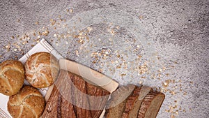 Organic rye bread, bagels, buns and toast bread appear on the table with sprinkling flour, rye and oats - Stop motion