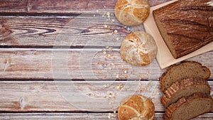 Organic rye bread and buns with sesame appear on wooden table - Sop motion