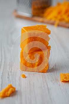 Organic Sharp Cheddar Cheese on a white wooden background, side view