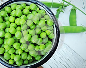 Organic sweet green peas in vintage cup on wooden white background.