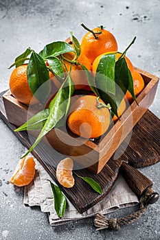Organic Tangerines, mandarins with green leaves in wooden box. Gray background. Top view