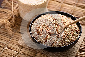 Organic Thai highland brown rice grain in a bowl with wooden spoon