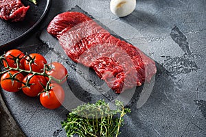 Organic tri tip, triangle  roast cut steak on black  slate raw meat , marbled beef over other alternative cuts  with herbs