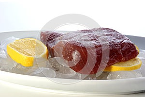 organic tuna steak on ice with lemon