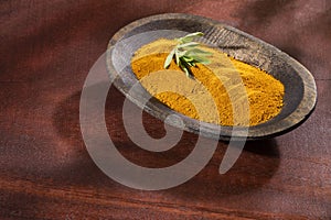 Organic turmeric powder in wooden bowl - Curcuma longa