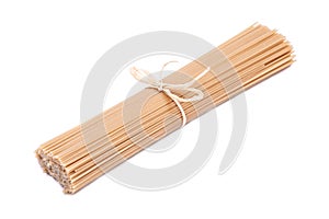 Organic uncooked Brown Rice Spaghetti pasta tied with a straw isolated on white background. Gluten-free and sodium-free