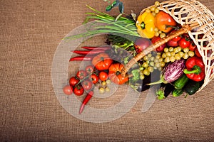 Organic vegetables, fruits and lettuce in wicker basket on kitchen table.