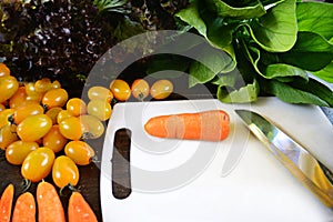 Organic vegetables ingredients around white cutting board with carrot and knife