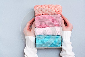 Organization and order. Women`s hands hold a box of neatly folded knitted clothes. Top view