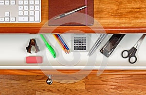 Organized desktop and open drawer with wooden floor underneath