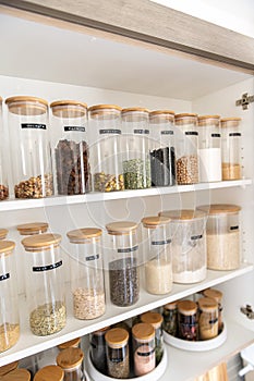 Organized labeled food pantry in a home kitchen with spices grains flour rice sugar nuts