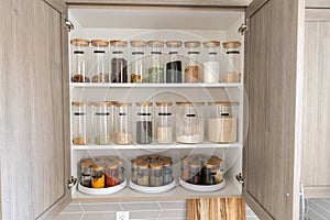 Organized labeled food pantry in a home kitchen with spices grains flour rice sugar nuts