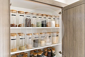 Organized labeled food pantry in a home kitchen with spices grains flour rice sugar nuts