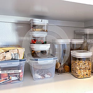 An organized pantry shelf with various types of cookies  cereal and snacks and snacks